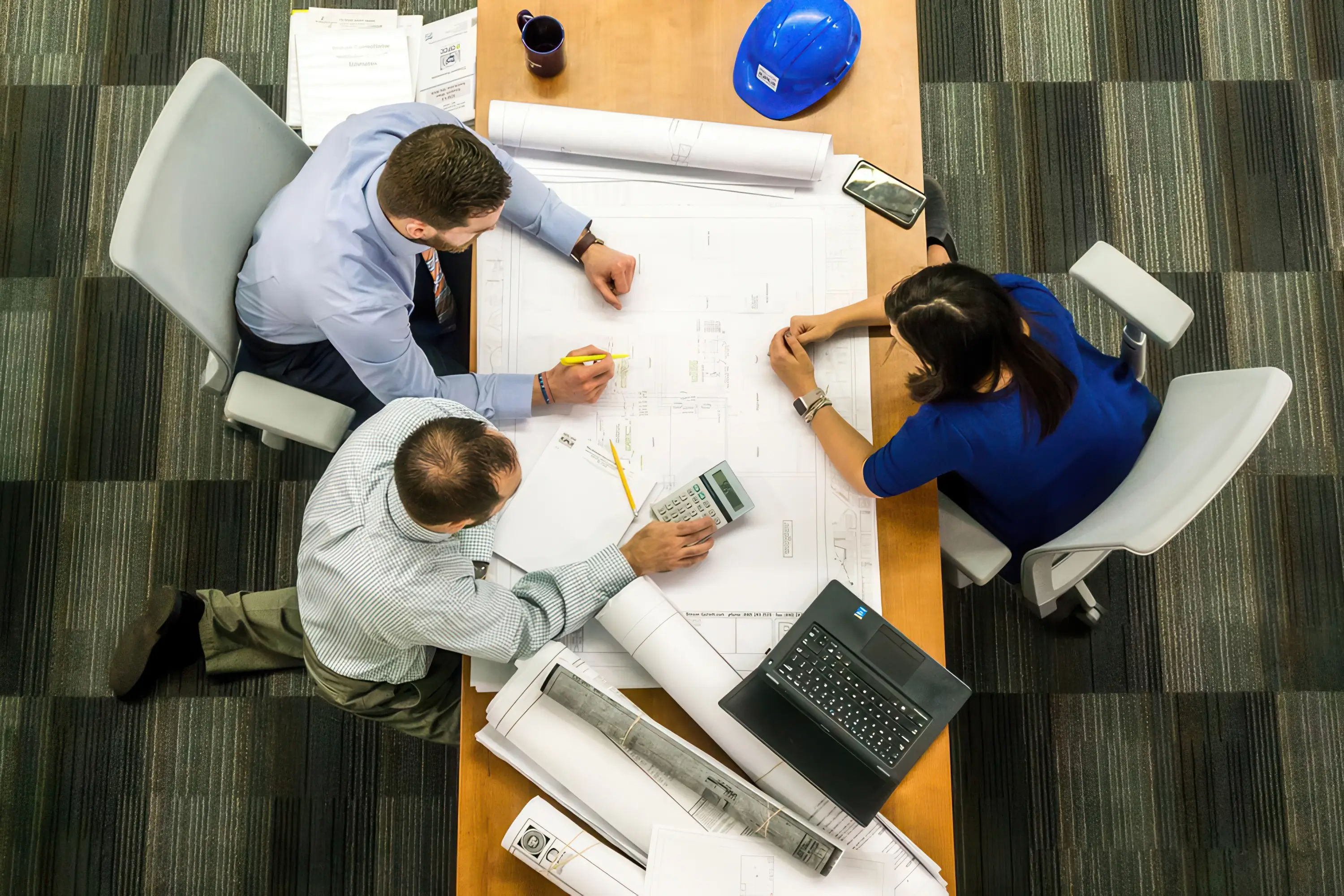 Employees sitting at a desk looking at plans