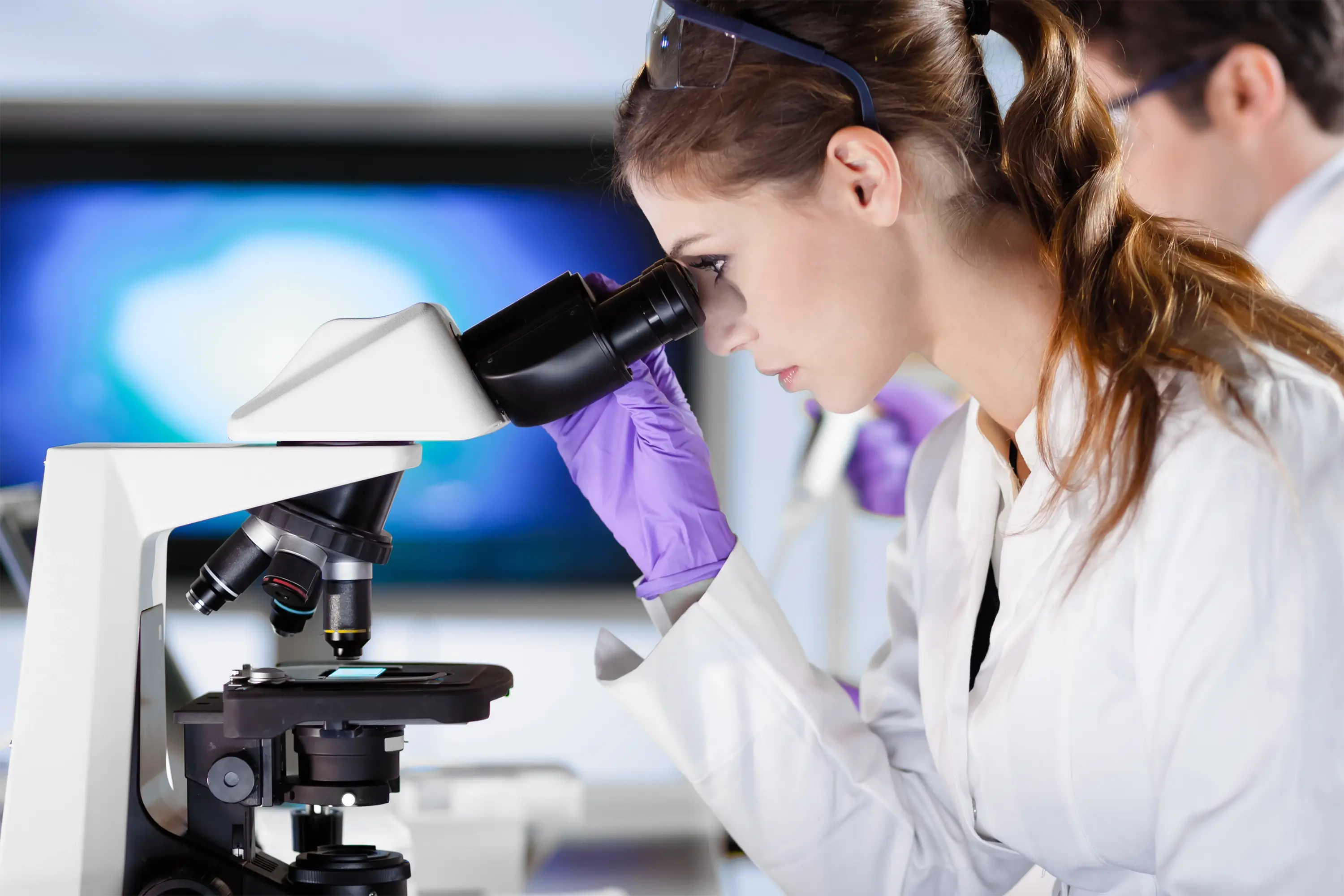 A stock photo of a woman using a microscope