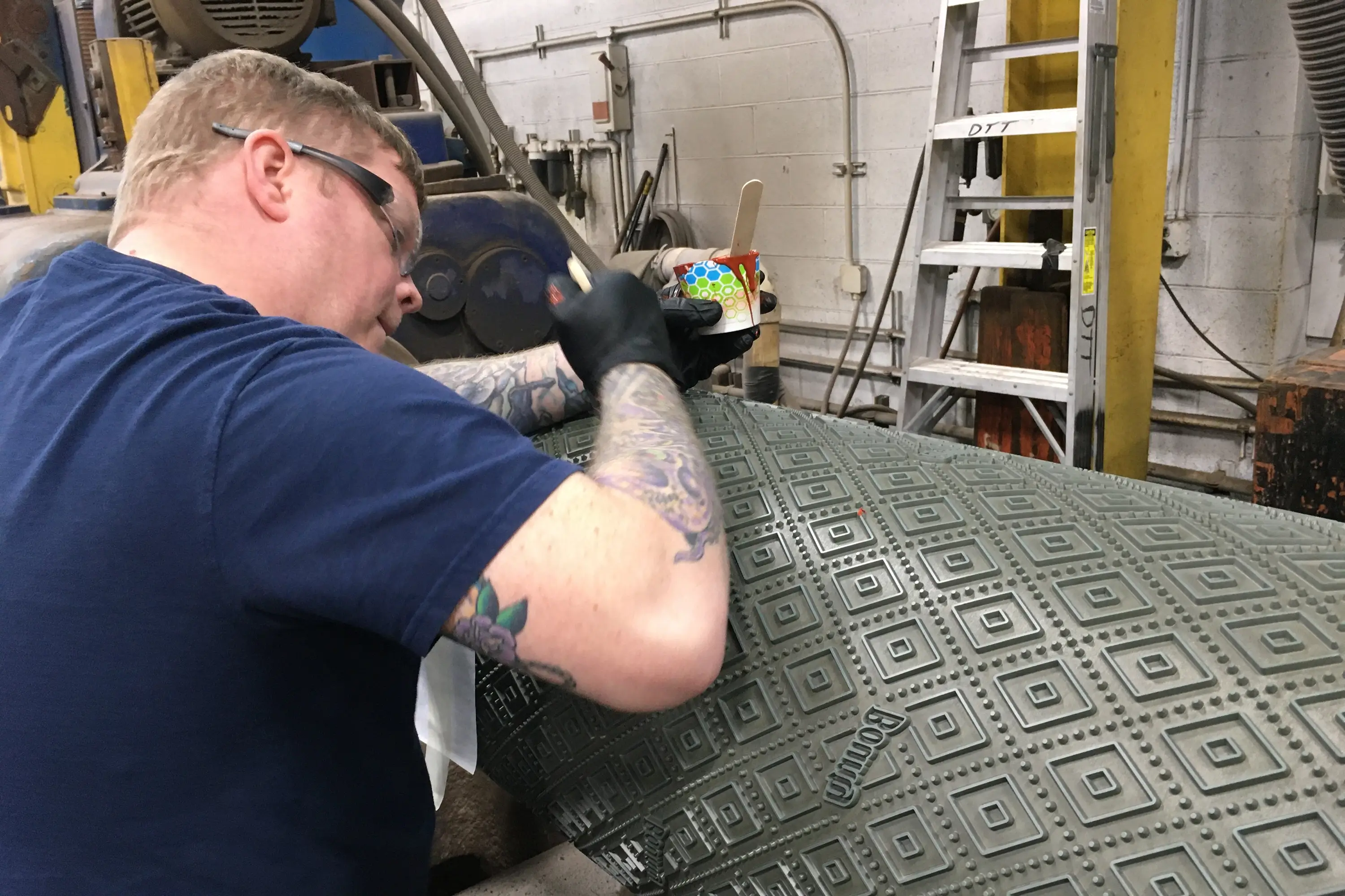 A man applying paint to a print roller