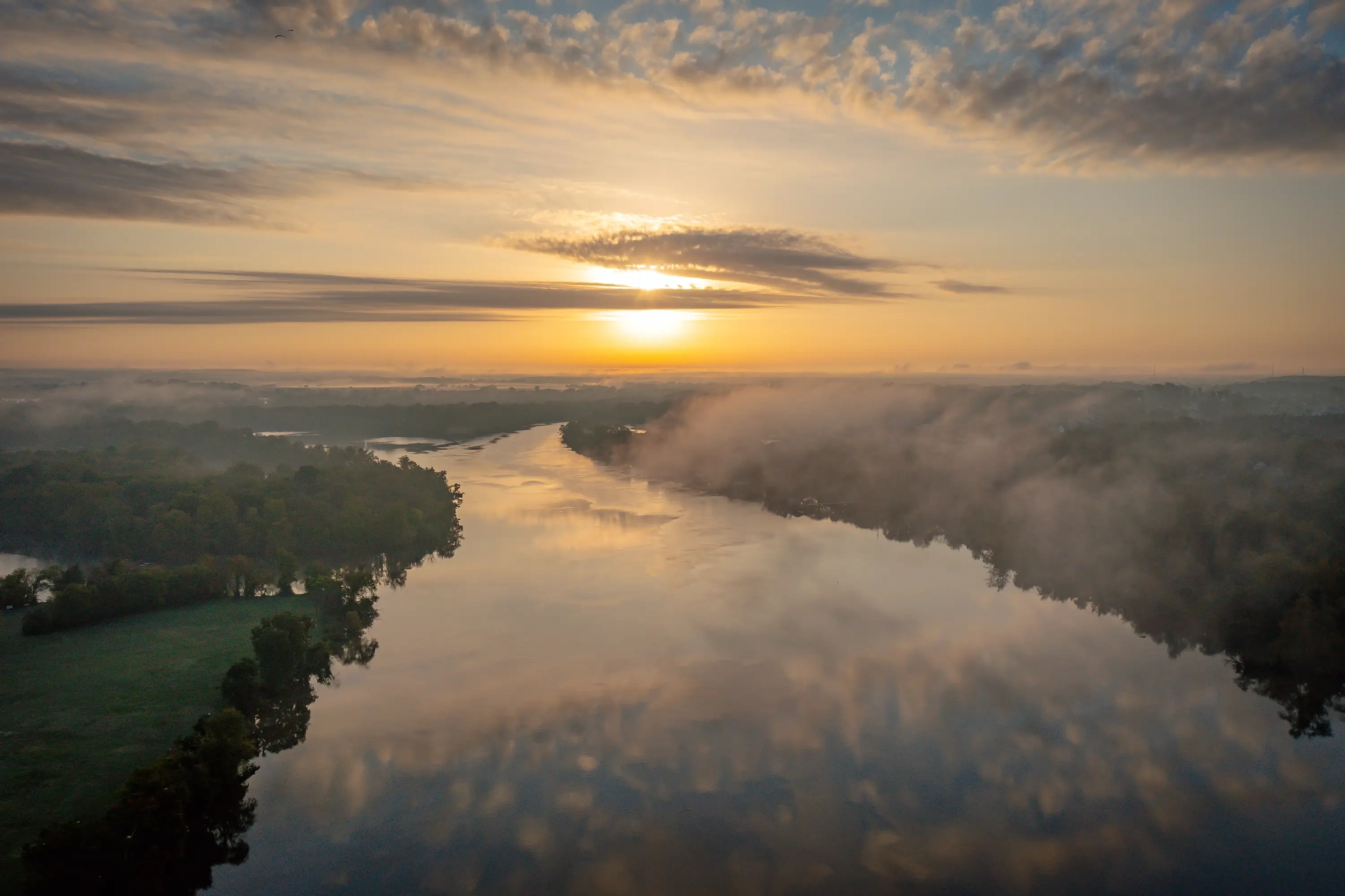 A scenic drone shot of a river near sunset